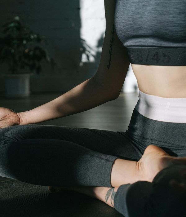 Woman in a calm yoga pose in a minimalist dark room.